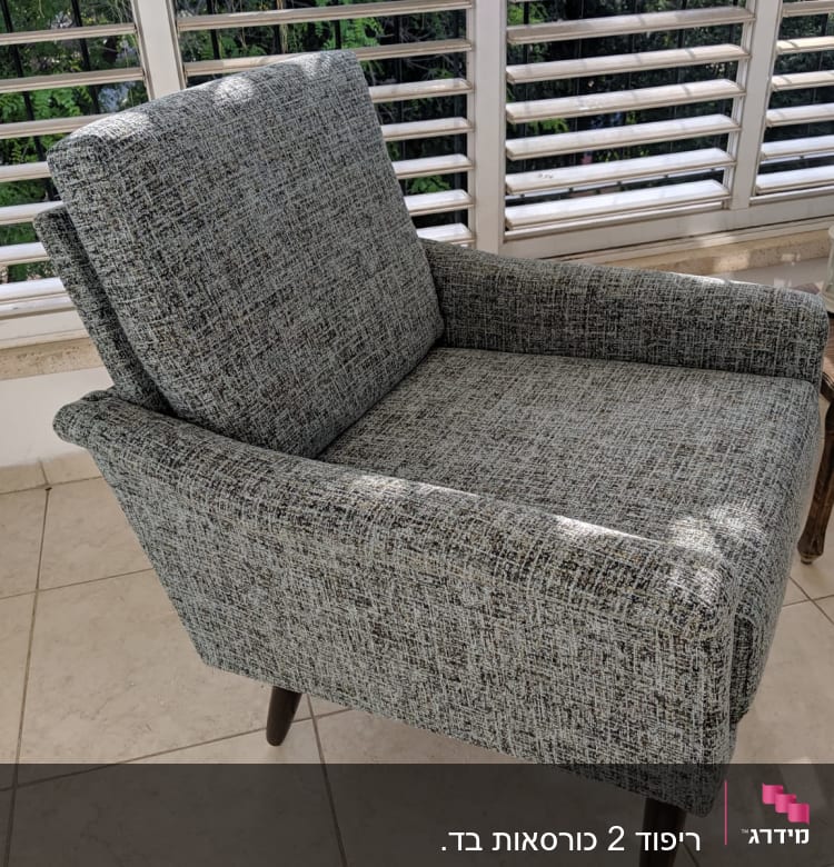 כורסה מרופדת בבד אפור עם רגלי עץ